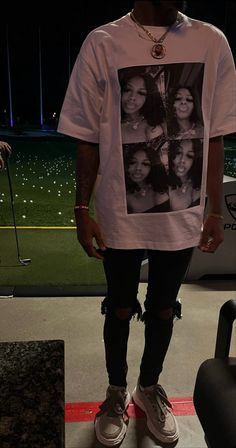 a man standing in front of a baseball field wearing a t - shirt with photos on it