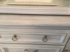 a white dresser with two handles and knobs