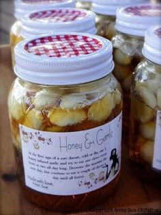 jars filled with honey and garlic sitting on top of a wooden table next to each other