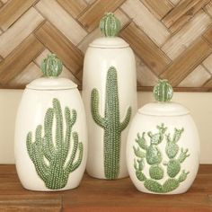 three ceramic cactus containers on a wooden shelf