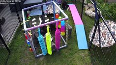 an outdoor play area with toys and umbrellas on the grass in front of a fence