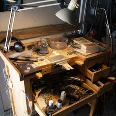 an old workbench with many items on it and a lamp in the background