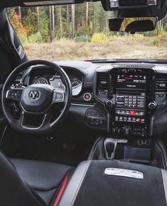 the interior of a vehicle with dashboard, steering wheel and dash board in front of trees