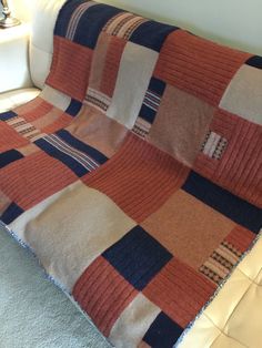 an orange and blue blanket sitting on top of a couch