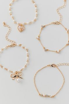 four different bracelets with charms and hearts on the clasp, all in gold tone