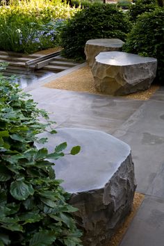 two stone benches sitting in the middle of a garden