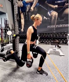 a woman doing squats with kettles in a gym