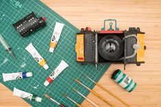 the contents of an old fashioned camera are laid out on a cutting board with tools