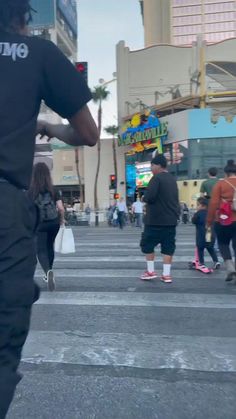 people are walking across the street in front of buildings