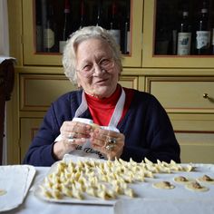 an older woman sitting at a table with food on it