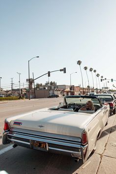 an old car is parked on the side of the road with other cars behind it