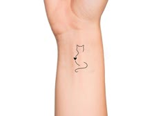 a small tattoo on the wrist of a woman's hand with a cat design