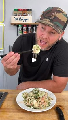 a man is eating noodles with chopsticks in his mouth while sitting at a table