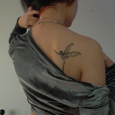 the back of a woman's shoulder with a dragonfly tattoo on her left arm