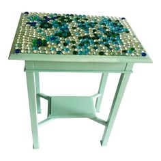 a white table topped with lots of blue and green beads on it's top