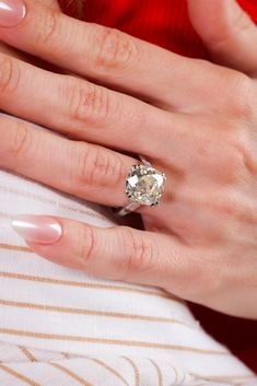 a woman's hand with a diamond ring on her left hand and white fingernails