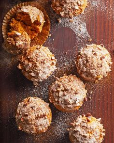 several muffins with powdered sugar on top sitting on a wooden table next to each other