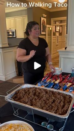 a woman standing in front of a table filled with tacos and other food