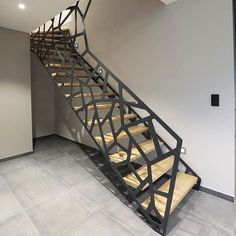 a metal stair case with wooden treads in an empty room next to a wall