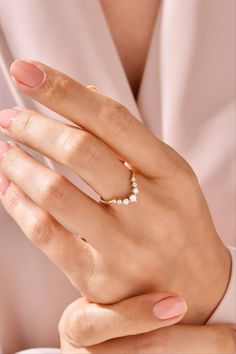 a woman's hand wearing a gold ring with three small white pearls on it