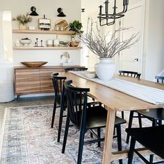 a dining room table with chairs and a vase on top of it in front of shelves