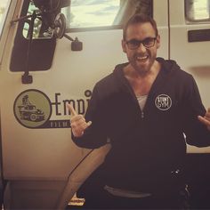 a man sitting in front of a truck giving the peace sign