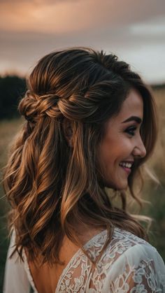 a woman with long hair wearing a white dress and smiling at the camera while standing in a field