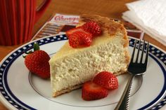 a piece of cheesecake with strawberries on a blue and white plate next to a fork