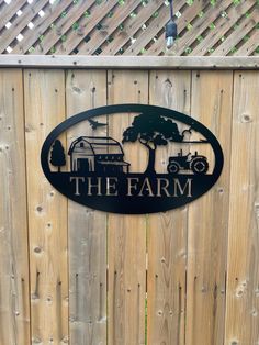 the farm sign is mounted on a wooden fence with trees and cars in the background