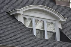 the roof of a house with two windows and a black shingled dormer on it