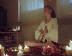 a woman sitting on the floor in front of candles