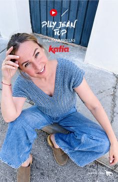 a woman sitting on the ground with her hand to her head and smiling at the camera