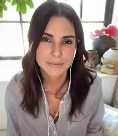 a woman with headphones on sitting in front of a window