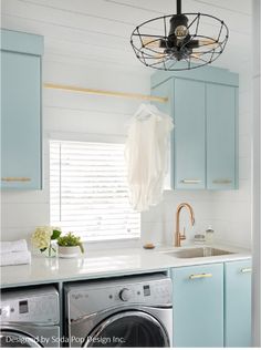 a laundry room with blue cabinets and a light fixture over the washer dryer