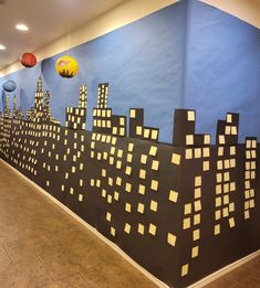 the wall is decorated with paper cut out city skylines and lanterns hanging from them