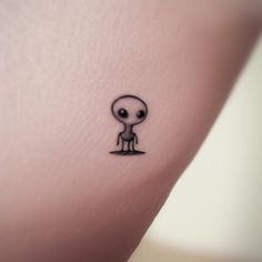 a small tattoo on the leg of a person with an alien head and legs in black ink