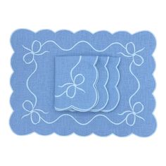 two blue place mats with white embroidery on them