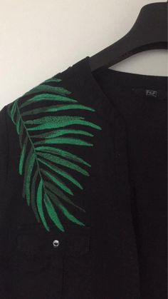 a black shirt with green leaves on it