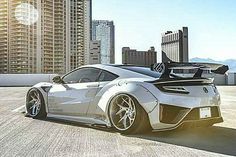 a white sports car parked in front of tall buildings with the city skyline behind it