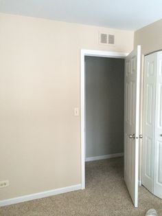 an empty room with white doors and carpet