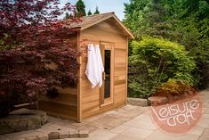 a small wooden shed with a towel hanging on it's door and trees in the background