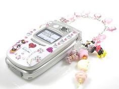 an old cell phone with charms attached to it