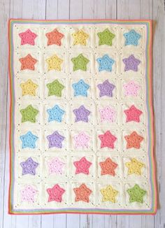 a crocheted baby blanket with stars on the front and bottom, in pastel colors