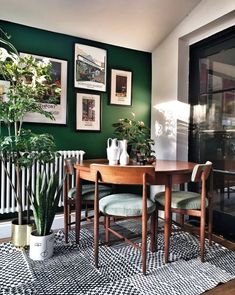 a dining room with green walls and pictures hanging on the wall above the dinning table