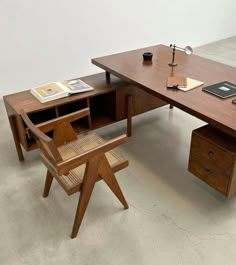 a wooden desk with a chair next to it and an open book on the table