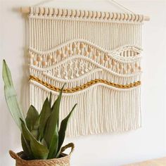 a potted plant sitting next to a macrame wall hanging