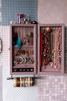 a purple box with jewelry hanging from it's sides on a wall next to other items