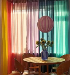 a dining room table with chairs and a vase filled with flowers