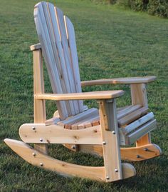 a wooden rocking chair sitting on top of a lush green field