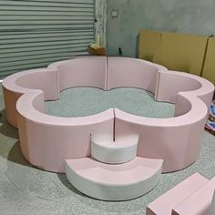 a pink circular bench sitting on top of a cement floor next to boxes and cardboard